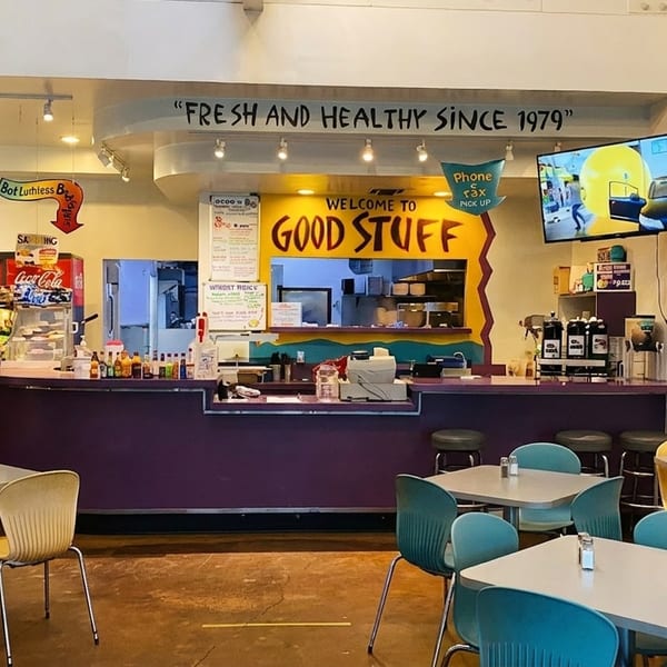 Interior of a casual restaurant with a purple counter, colorful chairs, and a "Welcome to Good Stuff" sign.